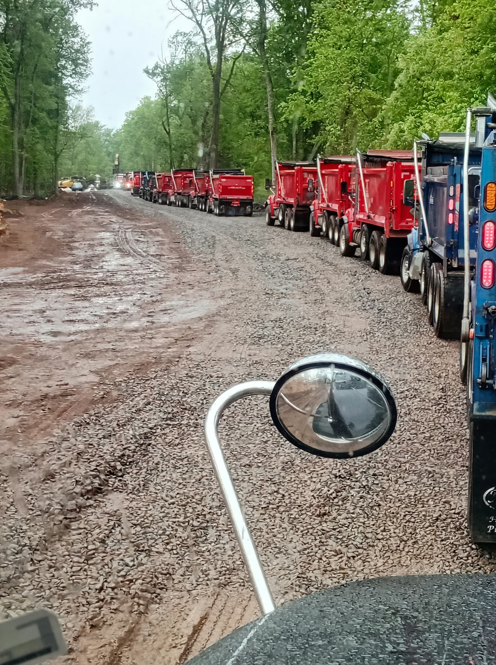 Logitech Transport dump trucks lined up on a dirt job-site road